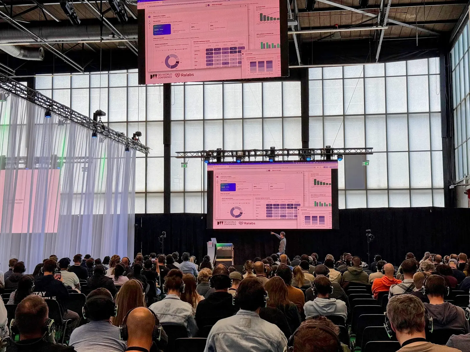 A full hall at DevWorld watching Roman's talk, with the slides on two big screens.