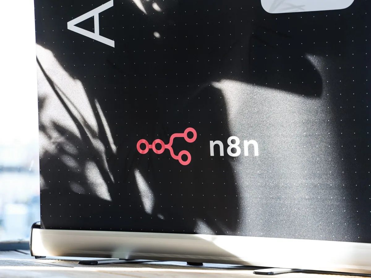 An n8n roll-up banner with the pink n8n logo, in the late-afternoon sun.